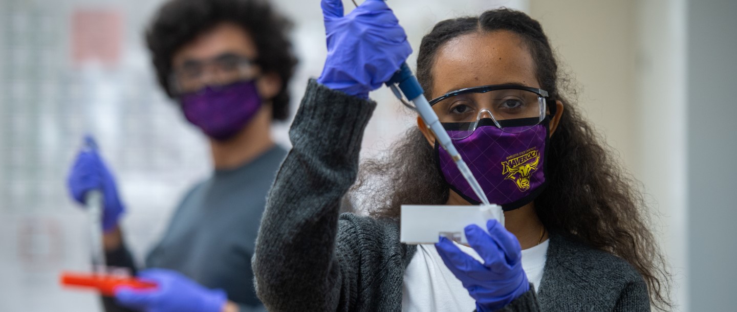 Two students doing test in the lab with maverick masks on