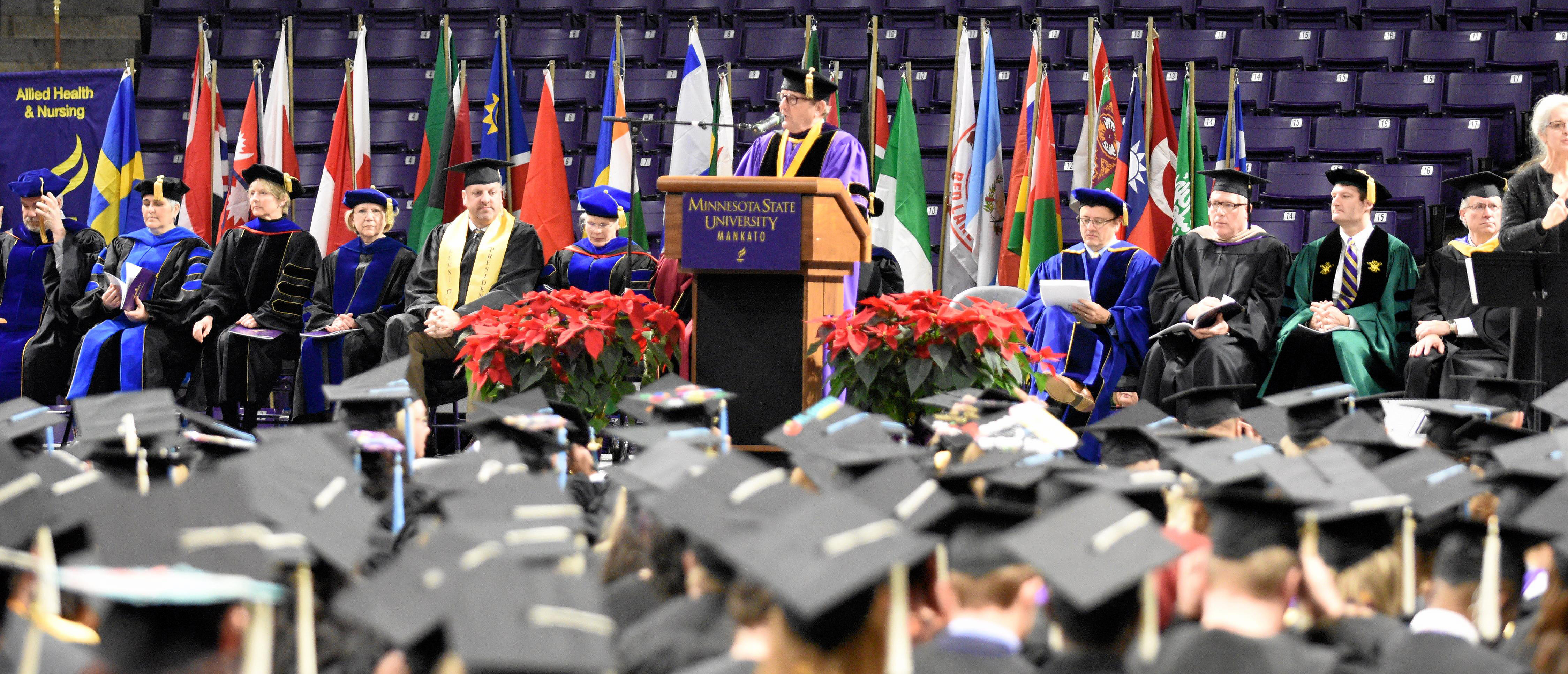 International flags displayed on commencement stage as President Davenport speaks