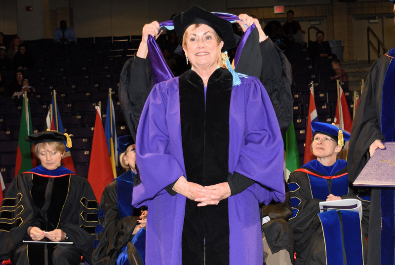 graduate being hooded with a Master's hood at graduation ceremony