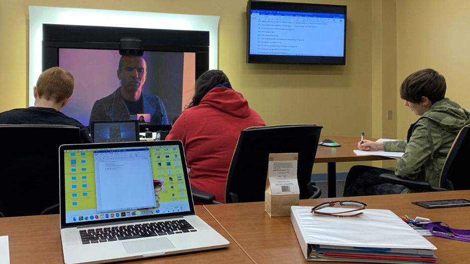 a group of people sitting at a table with laptops and a laptop on it