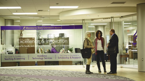 Faculty members having a conversation in front of the Center for Excellence and Innovation