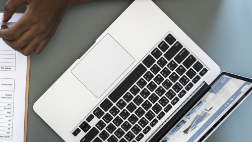 Top view of a laptop and clipboard on a desk