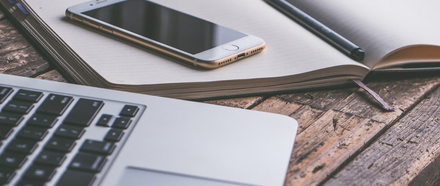 Laptop and a notebook with a mobile phone on top of the notebook