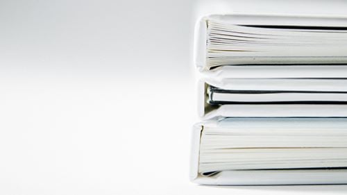 A stack of three binders filled with paper on a table
