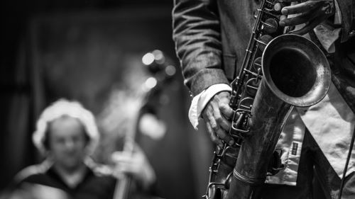 A musical jazz group with close up of someone playing the saxophone and someone playing an upright bass in the background