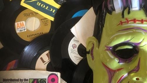Closeup of scattered records, newspapers and a Frankenstein mask 