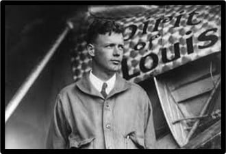 A black and white photo of Charles Lindbergh, an air-mail pilot, standing next to an airplane called the Spirit of St. Louis