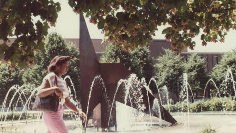 a person walking in front of a fountain