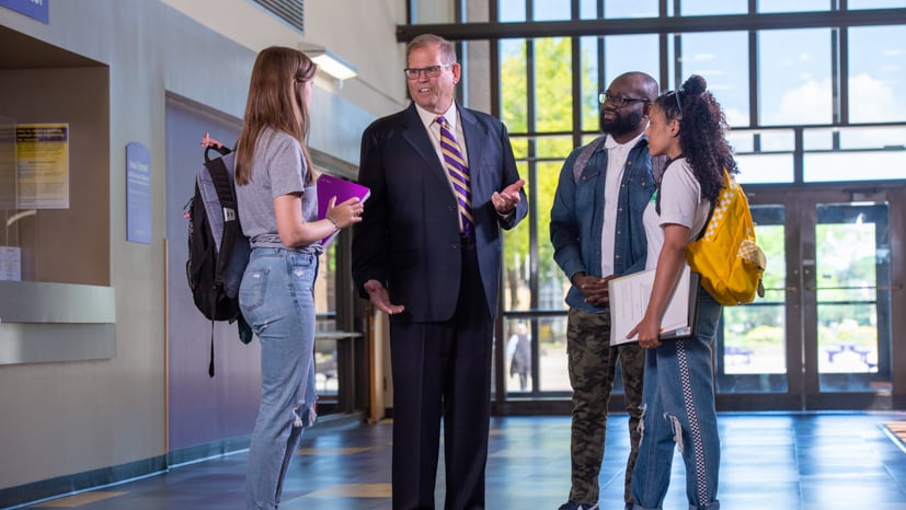 a person in a suit talking to a group of people