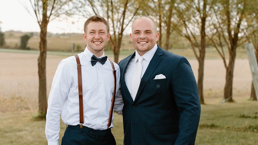 Matthew and Nathan at Nathan's wedding dressed in formal wear and big smiles on their faces.