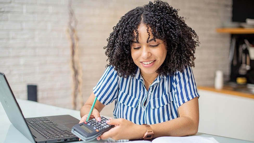 women working on her laptop with a calculator