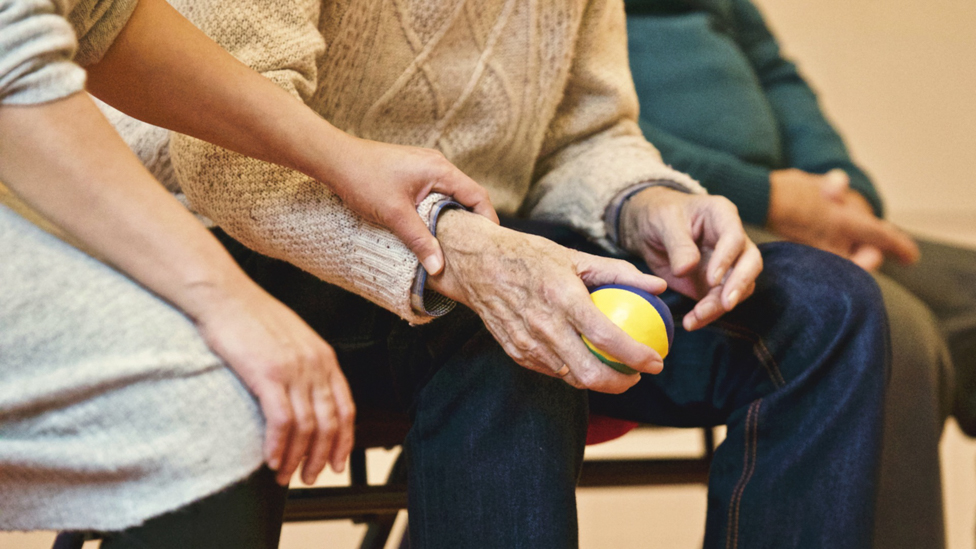 Aging gentleman working with ball in physical therapy.