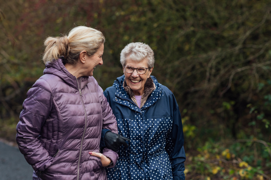 Aging women being escorted by a younger women in nature.