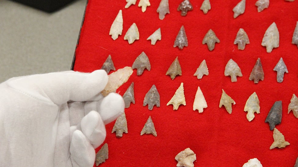 image of gloved hand looking at american indigenous artifacts