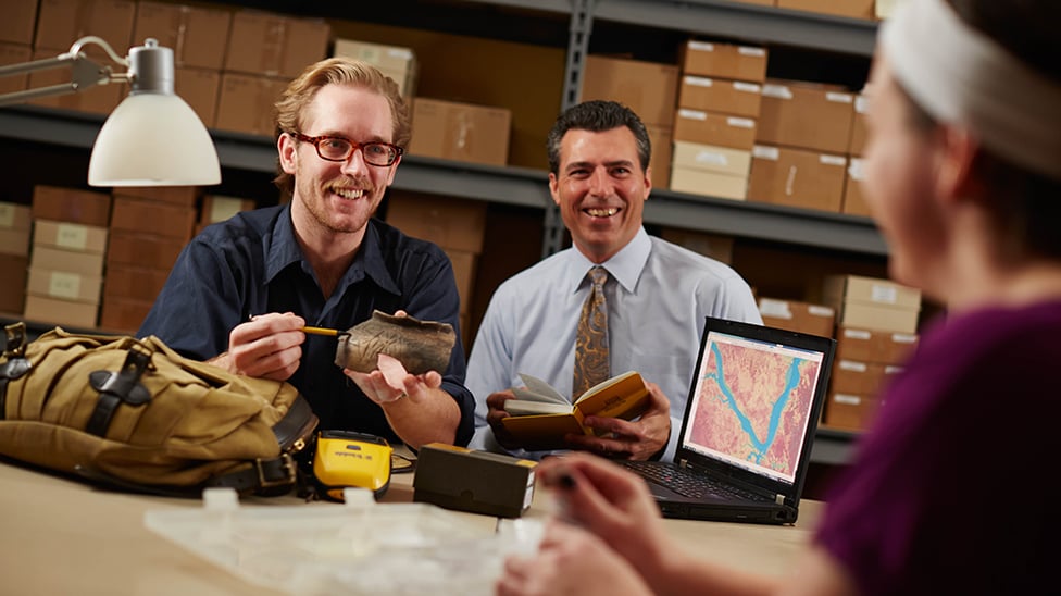 image of professor and two students looking at ancient artifacts