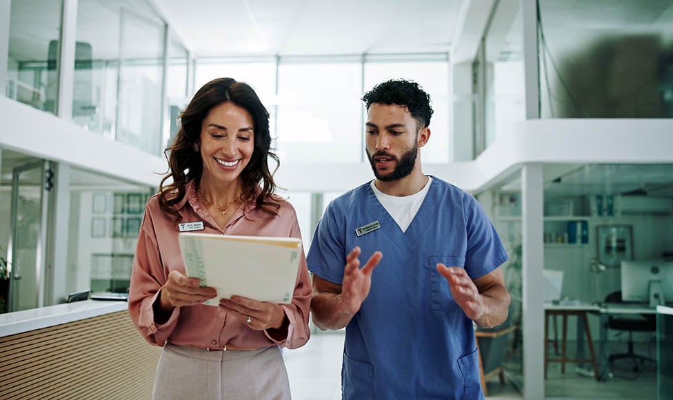 public health employee and a doctor walking and talking in a hospital setting