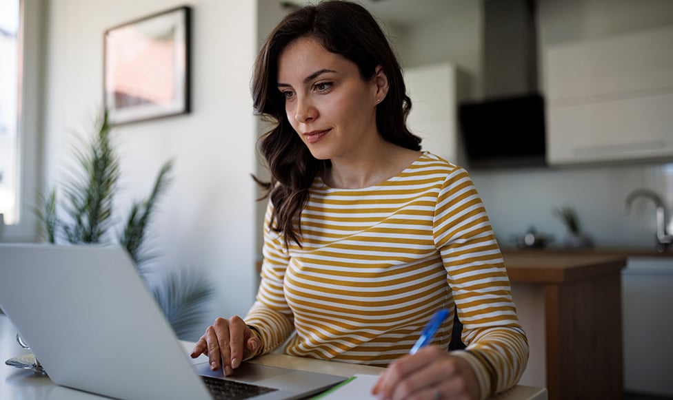 image of women working on computer while taking notes