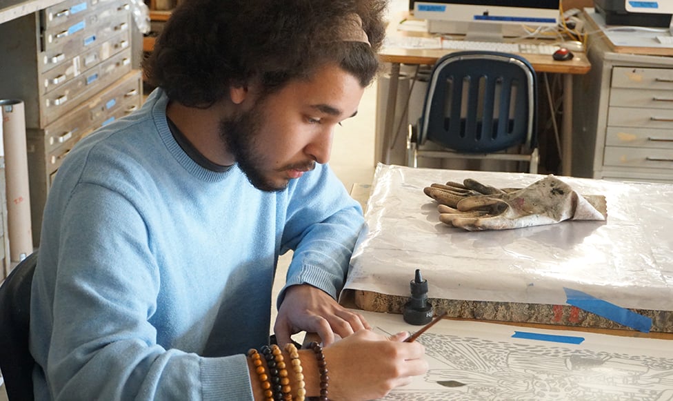 Male student drawing at table