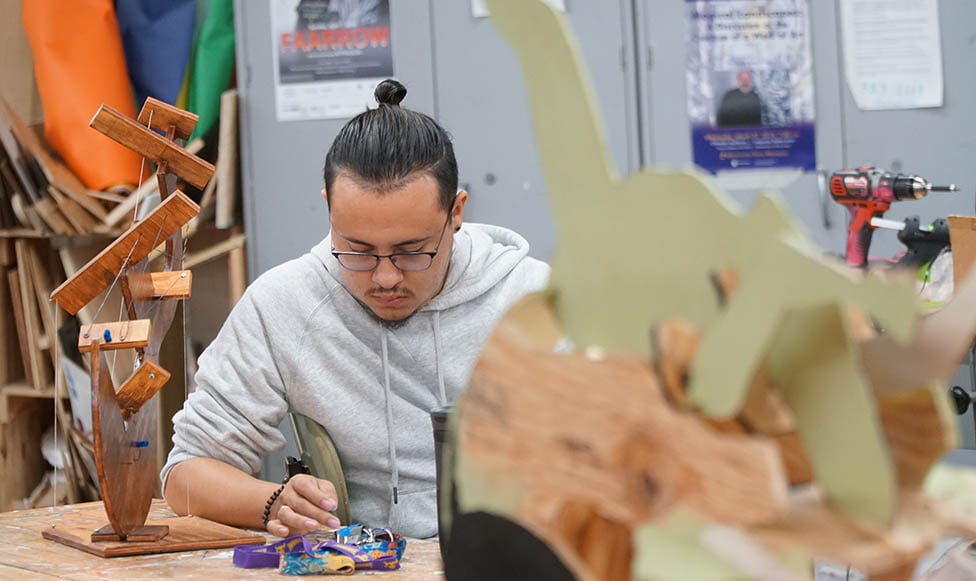 student working in an art studio surrounded by art