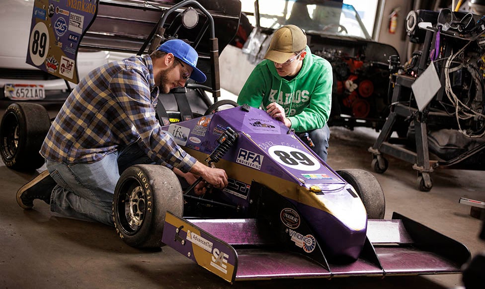 two students working on a race car
