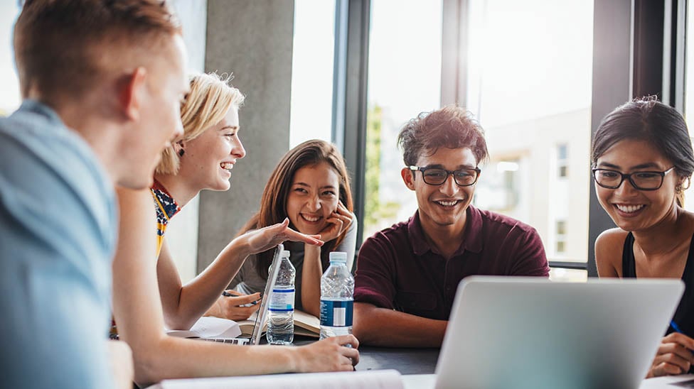 a group of students collaborating together while working on a laptop