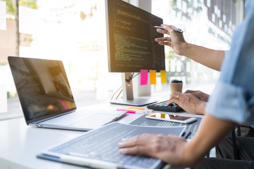 Pointing at computer screen with code on it. 