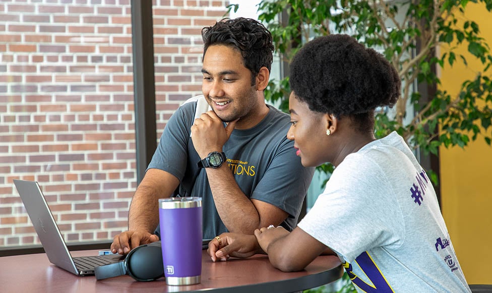 two students working on a laptop together