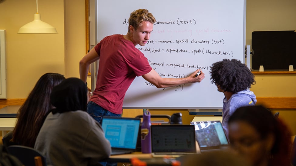 student pointing to board while leading a computer science study group