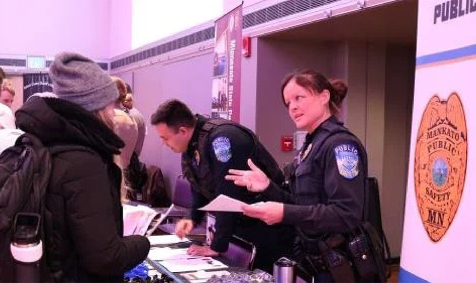 female police officer talking with students at career and internship fair