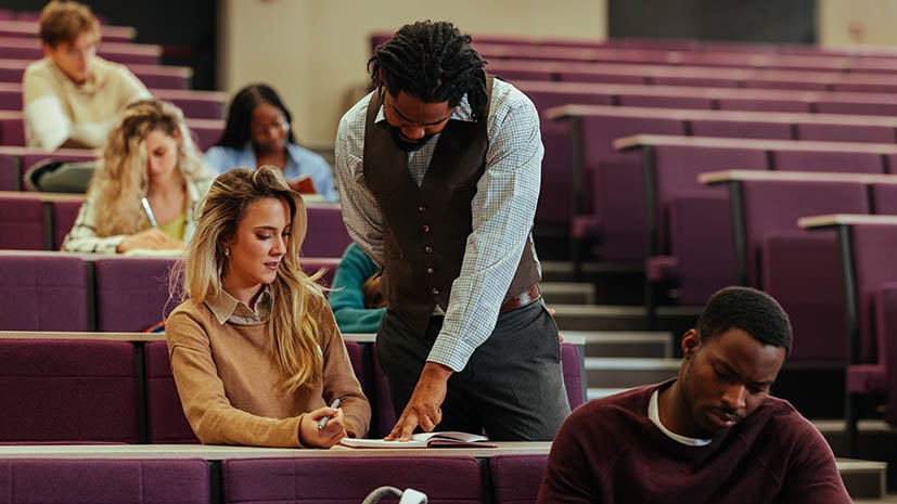 faculty member helping a college student in an auditorium