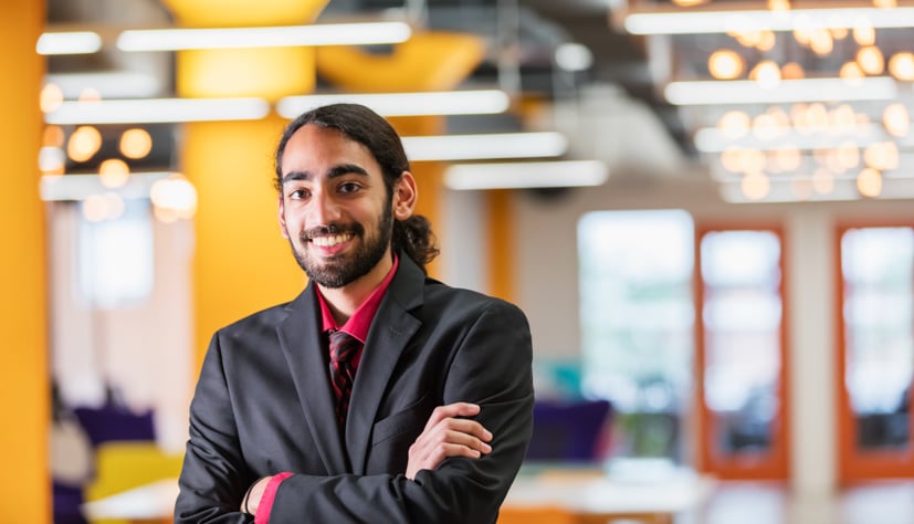 Male student facing camera, smiling with arms crossed wearing a suit.