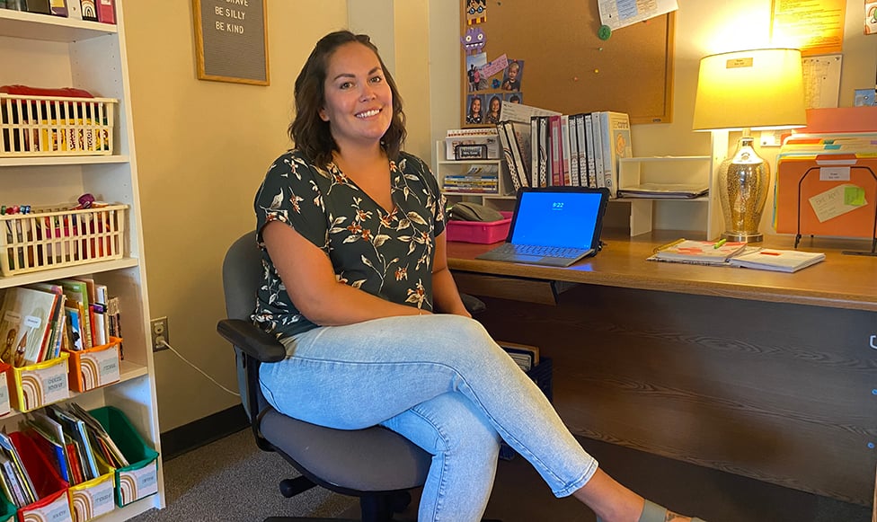 Support staff for students at desk smiling