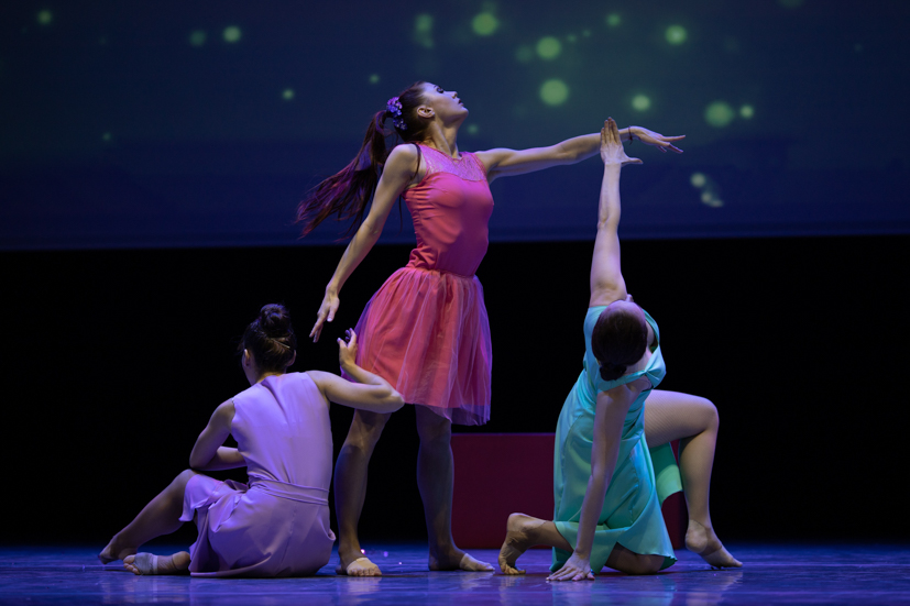 Three dancers dancing on stage.