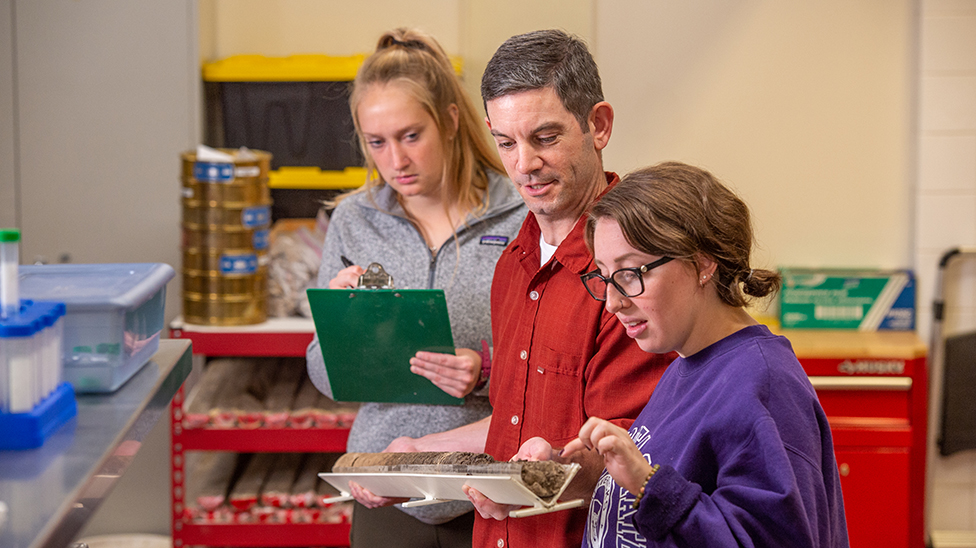 professor showing two students soil samples