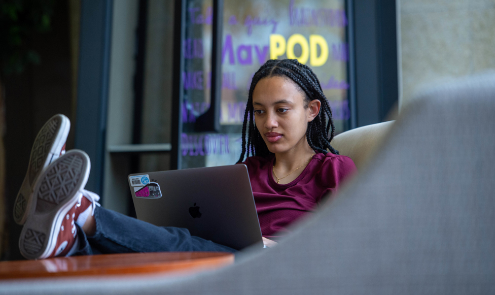 female student working on her laptop with her feet up on a table