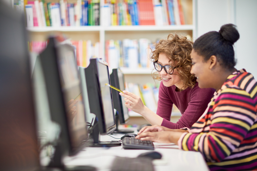 Teacher helping student on computer. 