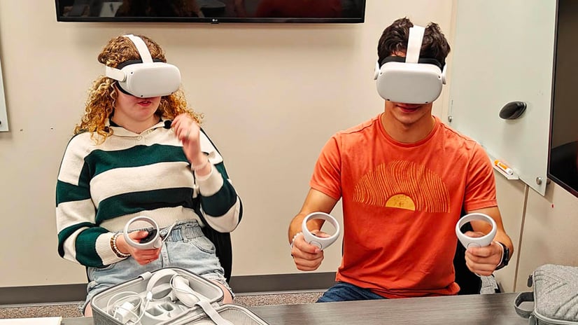 two students sitting in a classroom using virtual reality