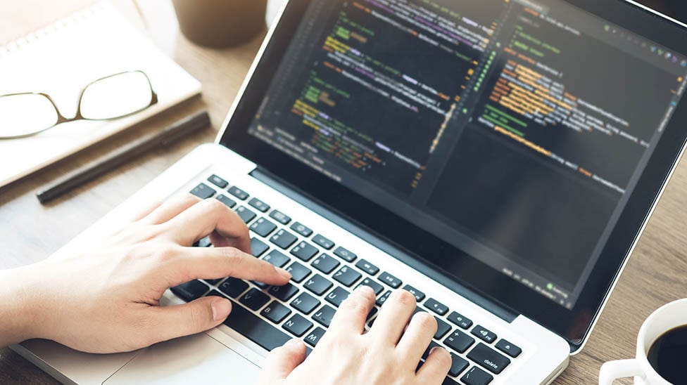 hands typing on a computer with code on the screen