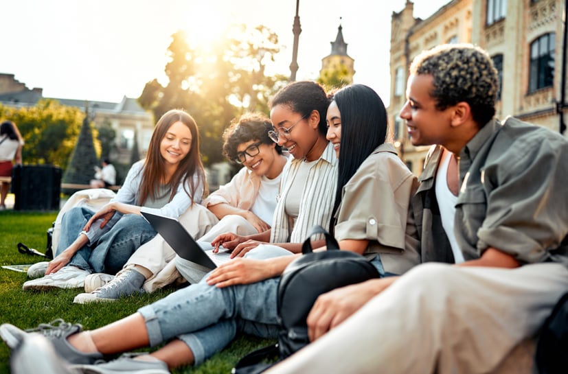 Group of diverse students sitting outside talking.