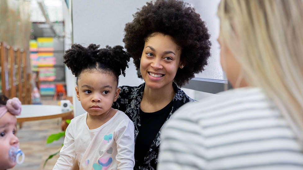 A mother with two small children are in a classroom with an educator