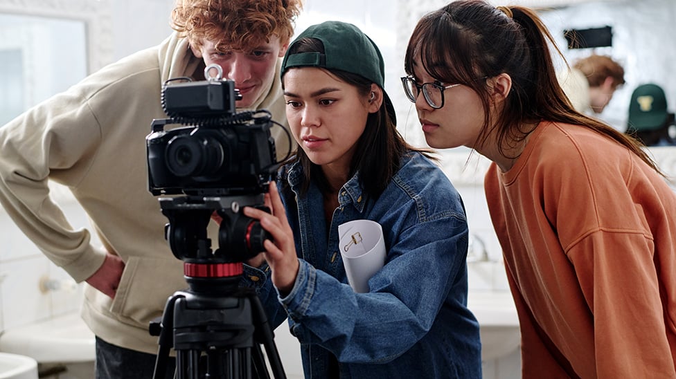 two women and one male student focusing a camera lens