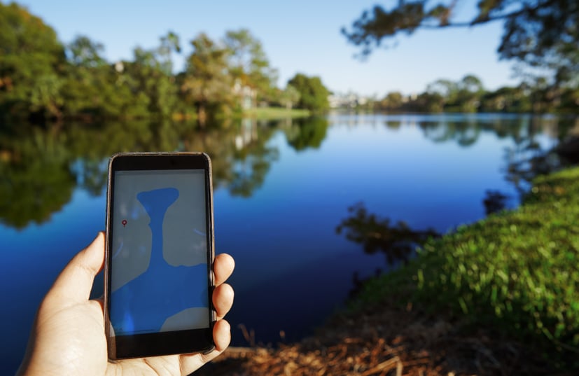 Map on phone being held by a hand, lake in the background.