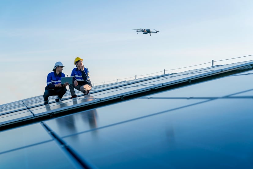 Two workers with construction hats using a drone.