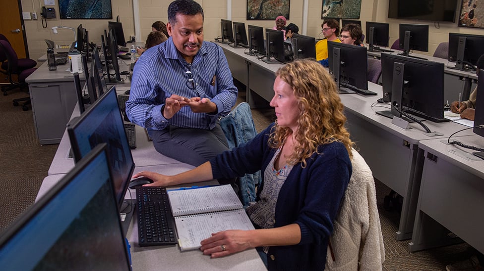 professor discussing geography with student at computer