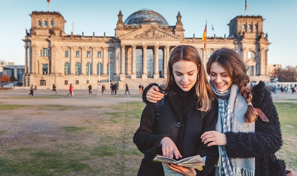 Two students in Europe in front of old building.
