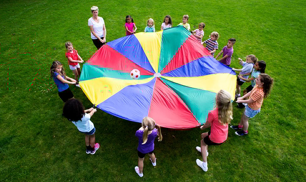 school age children with teacher holding a parachute