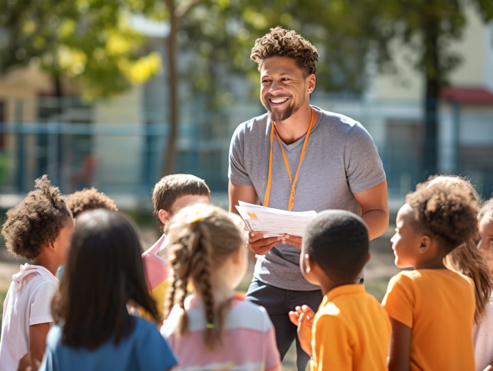 Elementary gym teacher talking with kids outside.