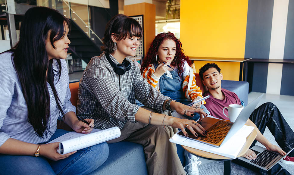 Casual group of young adults collaborating on a project with laptops in a contemporary office setting