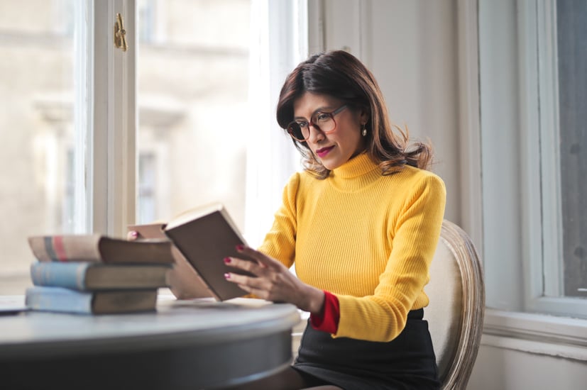 Woman reading a book at a desk.