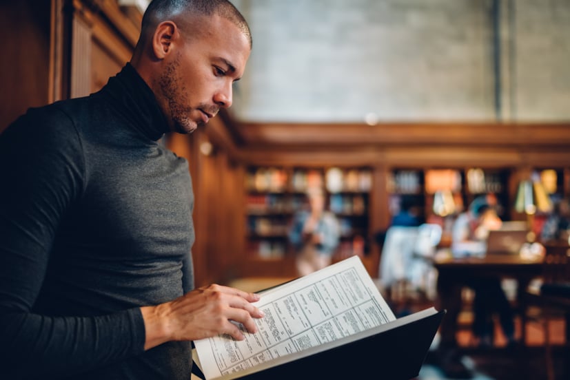 Man looking through a book in a library.